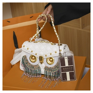 Detail of owl-shaped quilted crossbody bag with bead tassels and gold hardware