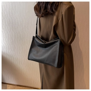 Detail of black lychee grain leather tote bag showing texture and shoulder strap fit