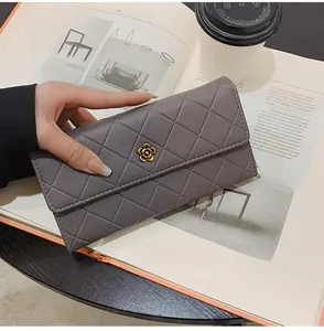 Detail of grey quilted long wallet with golden flower clasp in a lifestyle setting