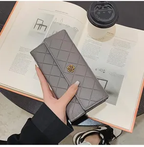 Close-up of grey quilted long wallet with golden flower buckle in a lifestyle setting