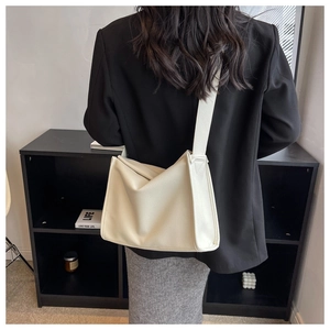Detail of the minimalist beige lychee grain leather tote bag with wide shoulder strap
