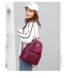 Side view of woman wearing quilted nylon backpack in burgundy with adjustable straps