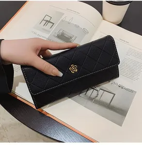 Detail of black quilted long wallet featuring a golden camellia clasp and pebble leather
