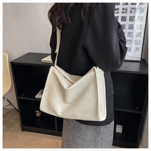 Detail of ivory lychee textured leather tote bag with adjustable wide strap on model