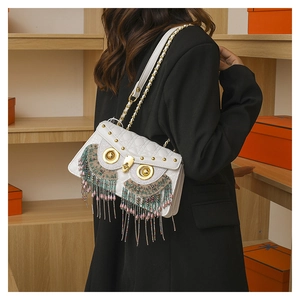 Detail of white quilted crossbody bag with golden owl eyes and colorful beaded fringe
