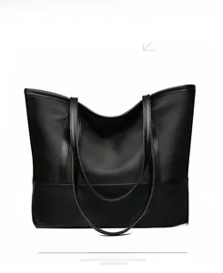 Detail view of The Wing bag in black faux leather with handle and visible stitching