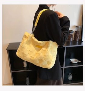 Detail of yellow plush tote bag with embossed heart pattern and silver chain strap