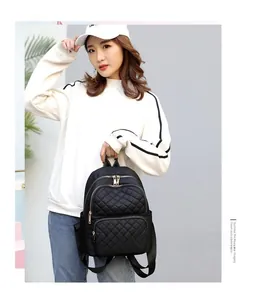 Detail view of black quilted nylon backpack with multiple compartments and golden zippers