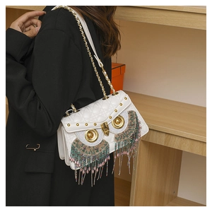 Detail of owl crossbody bag featuring beaded tassels and gold chain on shoulder