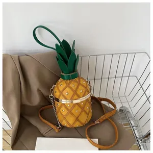 Détail du sac seau ananas jaune avec clous et feuilles vertes dans un chariot chic
