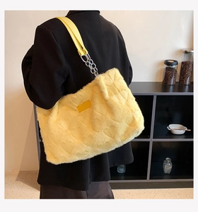 Side view of fluffy yellow faux fur tote bag with heart patterns and metal chain strap