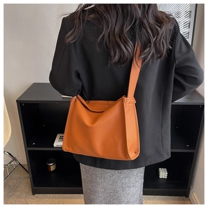 Detail of caramel lychee grain leather shoulder bag with wide strap on model