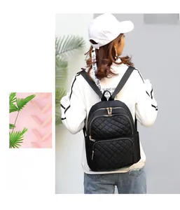 Detail of black quilted nylon backpack featuring branded webbing and metal zipper on model