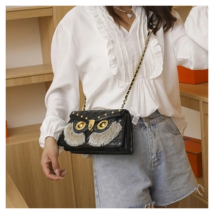 Detail of owl crossbody bag with quilted pattern, gold studs and silver fringe accents