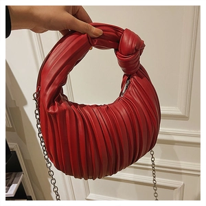 Détail du sac à main rouge plissé avec poignée nouée et bandoulière en chaîne argentée