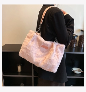 Close-up of pink faux fur tote bag featuring embossed heart patterns and leather strap