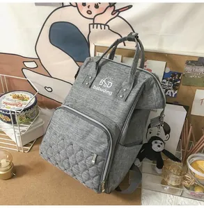 Detail of grey diaper backpack with quilted front pocket and plush monkey keychain