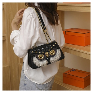Chic black quilted owl crossbody bag with metallic tassel eyes shown on a model