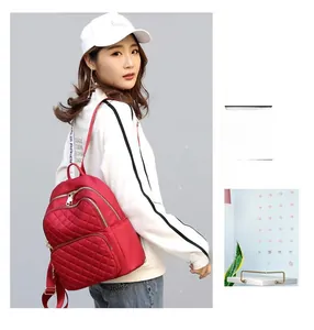 Detail of red quilted nylon backpack with golden hardware worn by a casual model