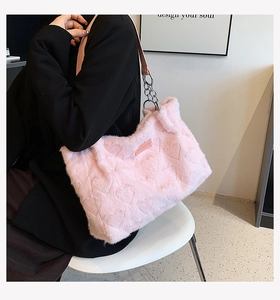 Detail of pink faux fur tote bag featuring embossed heart patterns and chain strap