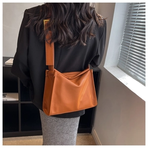Detail of caramel brown tote bag with premium lychee grain texture and gold buckle