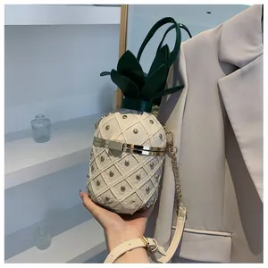 Détail du sac seau en forme d'ananas beige avec rivets dorés et feuilles vertes