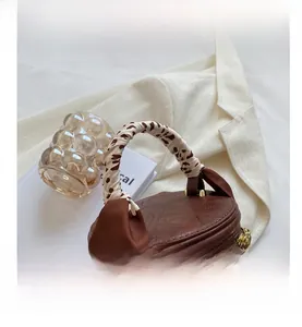 Détail d'un sac seau marron avec poignée léopard et décoration de nœud en satin
