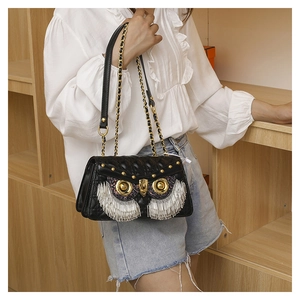 Detail of owl shaped black crossbody bag with silver fringe and gold metal owl eye accents