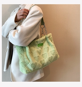 Detail of light green plush tote bag with embossed heart patterns and chain strap