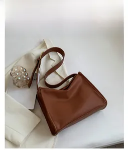 Detail of a brown lychee-textured tote bag with adjustable strap and golden hardware
