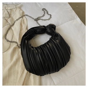 Détail de la texture en cuir noir plissé avec poignée à nœud et chaîne argentée