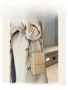Detail of a minimalist cream phone bag with lychee texture and silver chain strap