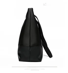 Detail view of reinforced stitching and textured black synthetic leather on tote bag
