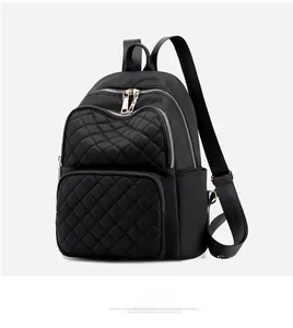 Detail of quilted nylon backpack featuring gold zippers and waterproof material texture