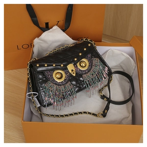 Detailed close-up of quilted owl handbag with colorful bead tassels in a gift box