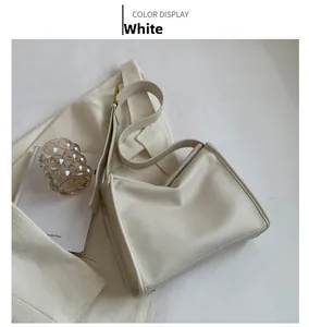 Close-up of white lychee-grain leather shoulder bag with gold metal buckle and strap