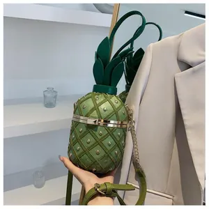 Détail du sac bandoulière vert en forme d'ananas avec clous métalliques et chaîne