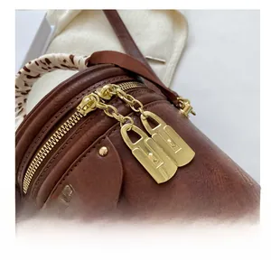 Gros plan détaillé du sac seau en cuir marron avec fermeture éclair dorée et foulard en soie