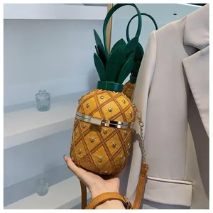 Détail du sac seau ananas avec texture jaune, rivets dorés et poignée en forme de feuilles