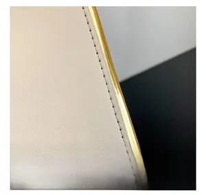 Close-up of beige leather bag showing precision stitching and smooth golden metal trim