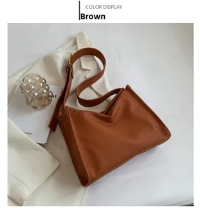 Detail of a brown lychee pattern leather tote bag with adjustable strap and golden buckle
