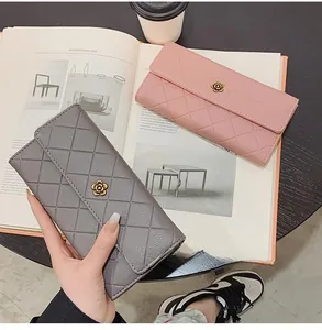 Close-up of quilted long wallets with flower clasp on a magazine in a lifestyle setting