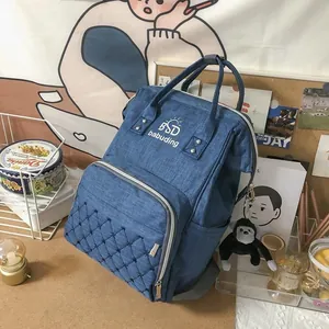 Detail of blue quilted mummy backpack featuring reinforced handle and plush charm accessory