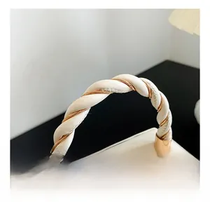 Detail of white leather twisted handle with gold metal accents on a fashion handbag