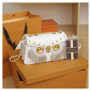 Detail of white quilted crossbody bag with golden owl eyes and silver fringe lashes
