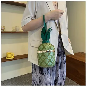 Détail du sac seau en forme d'ananas vert avec clous dorés et poignée en forme de feuilles