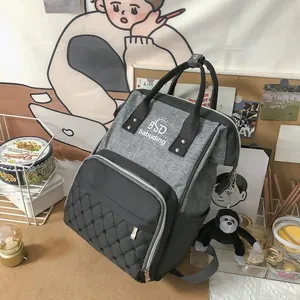 Detail of grey diaper backpack with quilted diamond pattern and a cute monkey charm