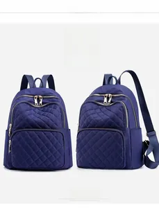 Detail view of dark blue nylon quilted backpack featuring classic diamond stitching pattern