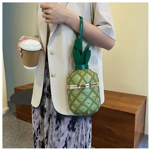 Vue détaillée d'un sac seau ananas vert avec clous dorés et poignée en forme de feuille