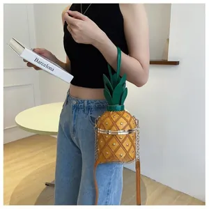Détail du sac seau ananas jaune avec chaîne dorée et poignée en forme de feuille